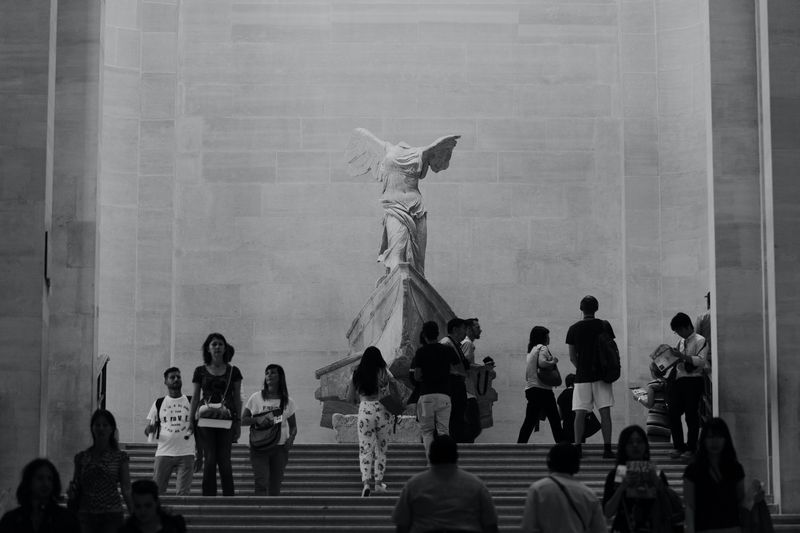 photo de visiteurs devant la Victoire de Samothrace, au Louvre